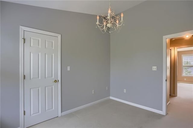 carpeted spare room with an inviting chandelier