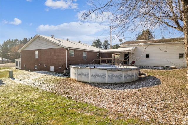 back of house with crawl space, a covered pool, and brick siding