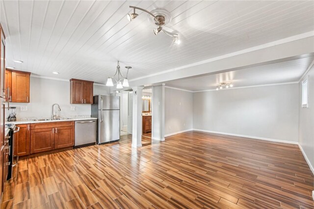 kitchen featuring appliances with stainless steel finishes, brown cabinets, ornamental molding, light wood-type flooring, and a sink