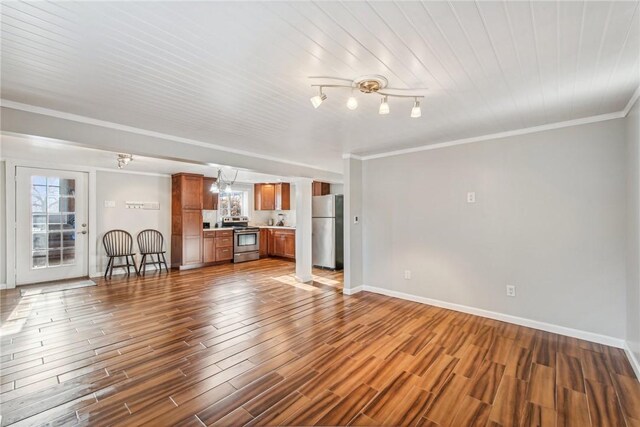 unfurnished living room featuring baseboards, dark wood-style flooring, plenty of natural light, and crown molding