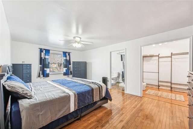 bedroom with a ceiling fan, wood-type flooring, ensuite bath, and baseboards