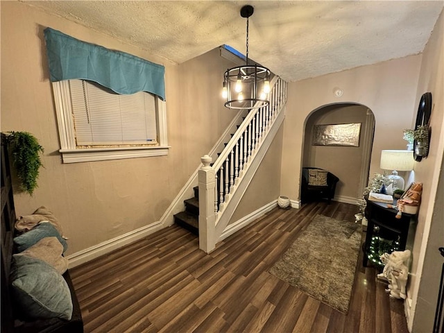 stairs with a chandelier, hardwood / wood-style floors, and a textured ceiling