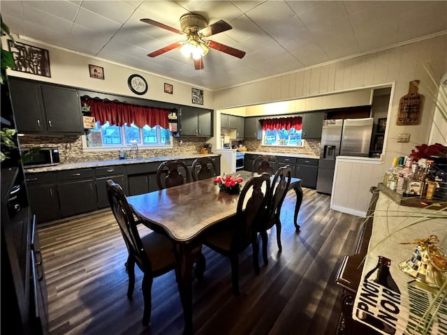 dining space with ornamental molding, ceiling fan, dark wood-type flooring, and sink