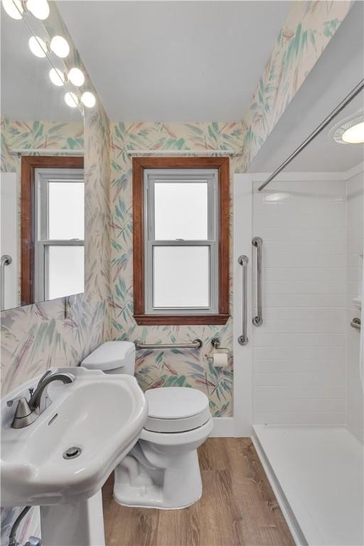 bathroom featuring toilet, hardwood / wood-style floors, a tile shower, and sink