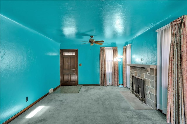 unfurnished living room with ceiling fan, a fireplace, and carpet