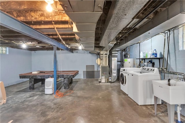 basement with heating unit, water heater, sink, and washer and dryer