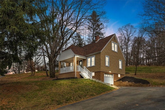 view of front of house with covered porch, a garage, and a lawn