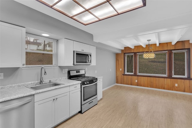 kitchen with sink, hanging light fixtures, beamed ceiling, white cabinets, and appliances with stainless steel finishes