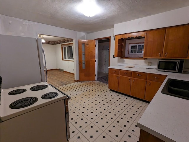 kitchen with a textured ceiling, light wood-type flooring, white appliances, and sink