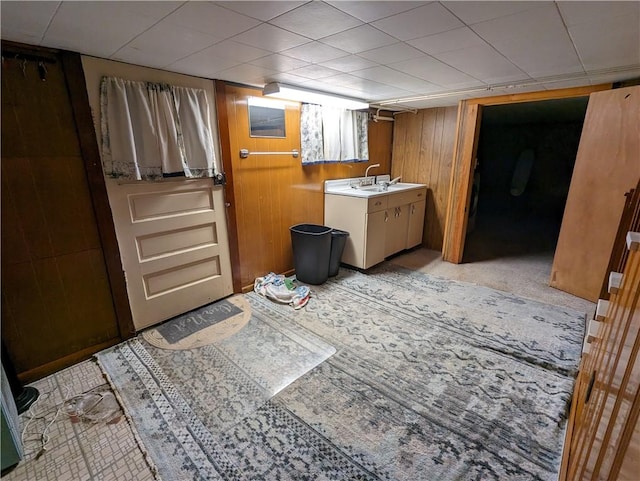 clothes washing area featuring cabinets, sink, and wooden walls