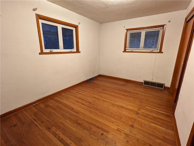 empty room featuring a textured ceiling and hardwood / wood-style flooring