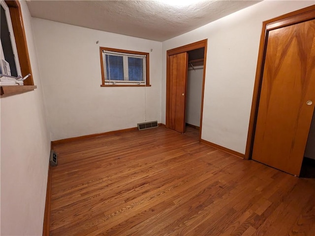 unfurnished bedroom with light hardwood / wood-style floors, a textured ceiling, and a closet