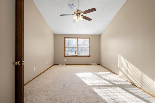 spare room with ceiling fan, light colored carpet, a textured ceiling, and vaulted ceiling