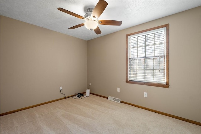 empty room featuring light carpet, ceiling fan, and a textured ceiling