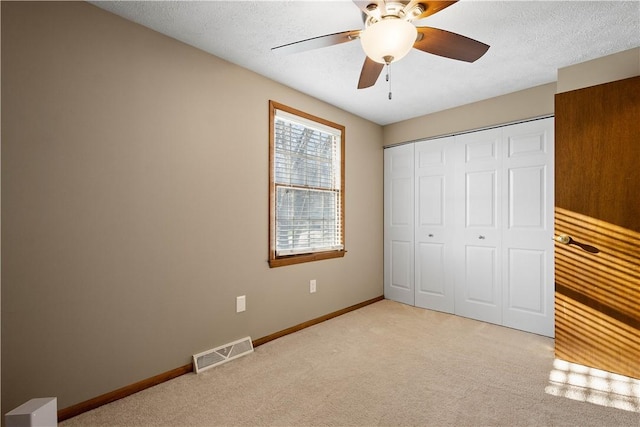 unfurnished bedroom with light carpet, a textured ceiling, a closet, and ceiling fan