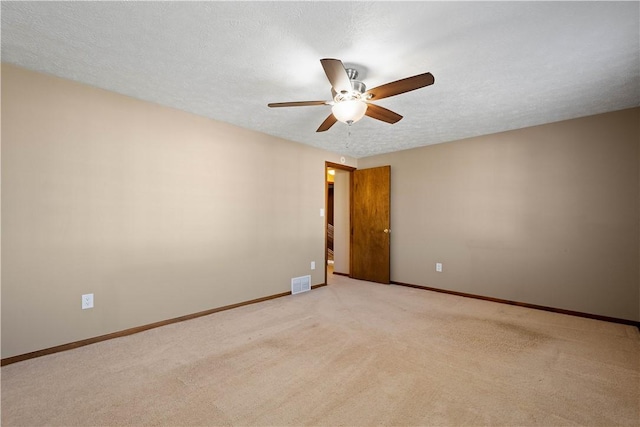 empty room featuring ceiling fan, light colored carpet, and a textured ceiling