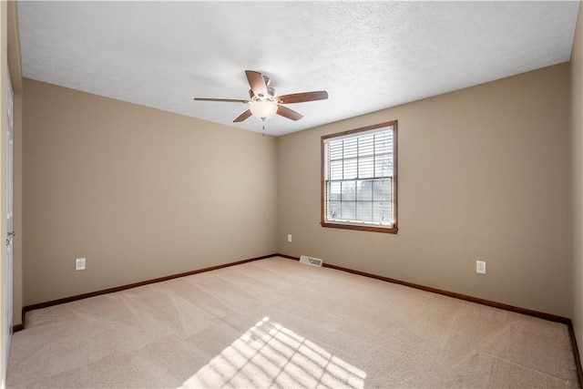 spare room featuring light carpet, ceiling fan, and a textured ceiling