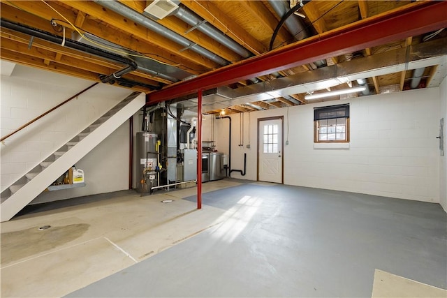 basement featuring washing machine and dryer, gas water heater, and heating unit