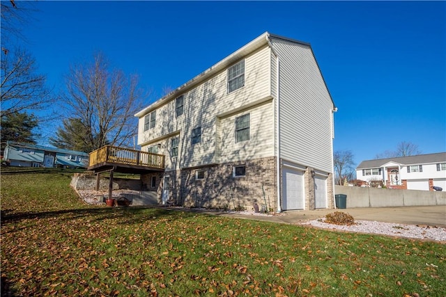 rear view of property featuring a garage, a deck, and a yard