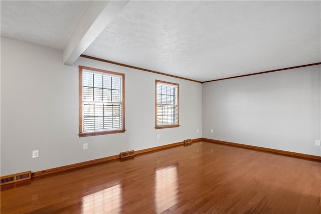 spare room with beamed ceiling, wood-type flooring, a textured ceiling, and ornamental molding