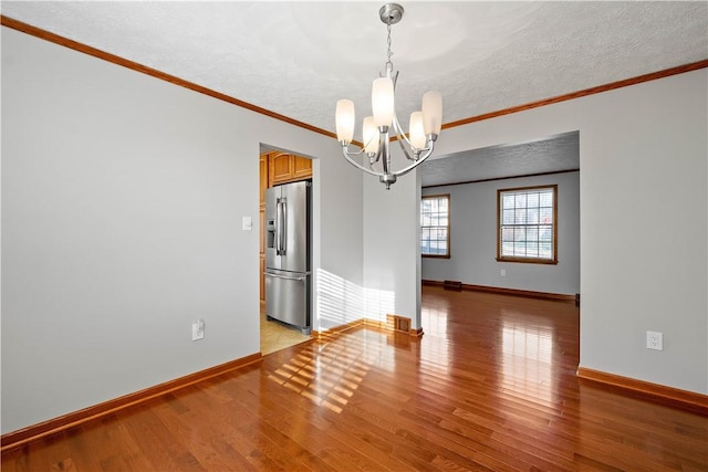 spare room featuring a notable chandelier, ornamental molding, a textured ceiling, and light hardwood / wood-style flooring