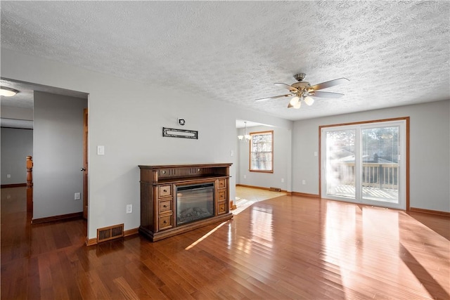 unfurnished living room featuring hardwood / wood-style floors, ceiling fan, and a textured ceiling