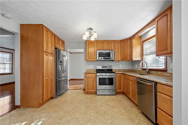 kitchen featuring a textured ceiling, sink, stainless steel appliances, and a wealth of natural light