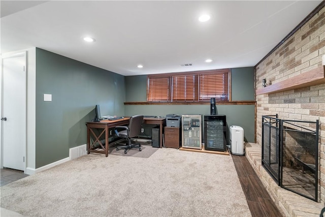 office area with hardwood / wood-style flooring and a brick fireplace