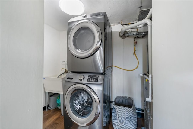 laundry room featuring dark hardwood / wood-style flooring and stacked washer and clothes dryer