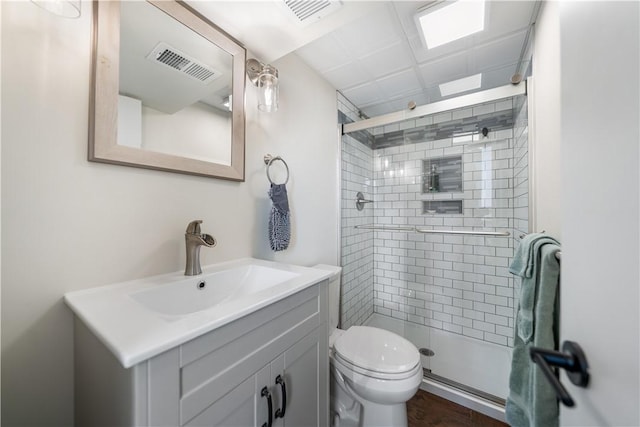 bathroom with a shower with door, vanity, and toilet