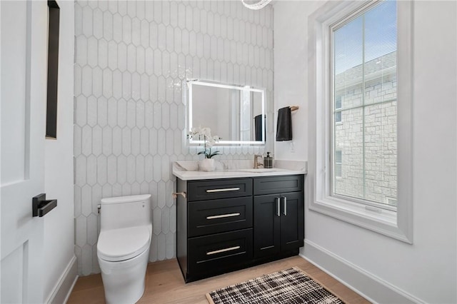 bathroom with a wealth of natural light, toilet, vanity, and hardwood / wood-style flooring