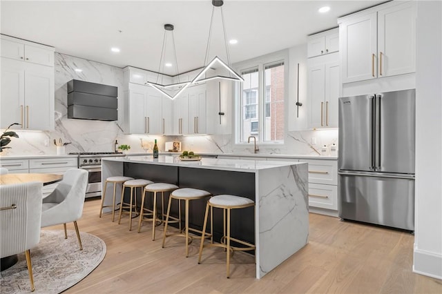 kitchen featuring light wood-type flooring, custom range hood, high end appliances, pendant lighting, and white cabinets