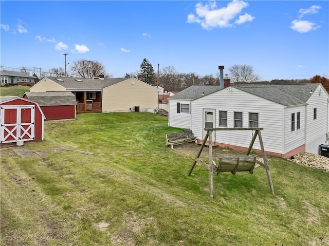 back of house with a lawn and a storage unit