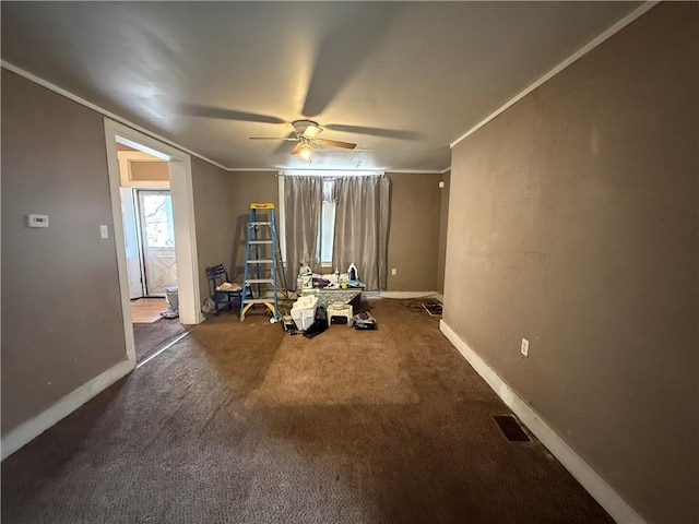 misc room with dark colored carpet, ceiling fan, and crown molding