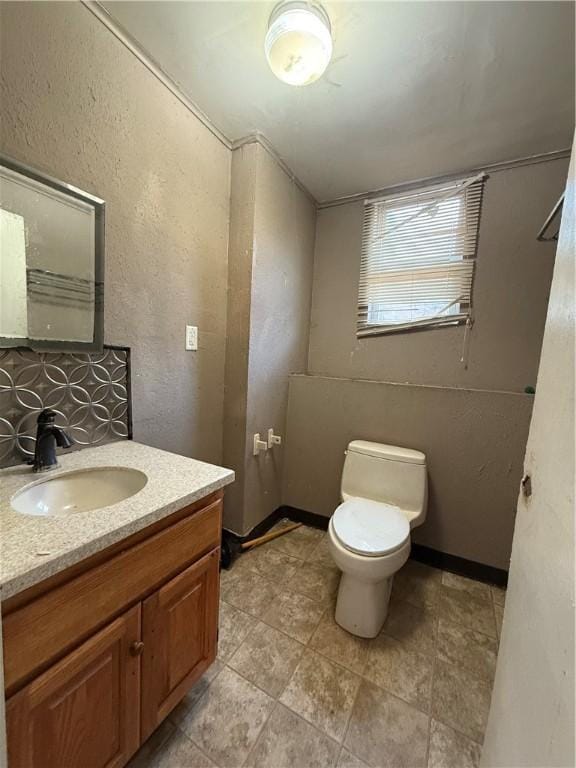 bathroom with vanity, backsplash, and toilet