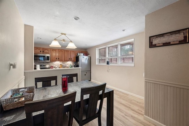 dining area featuring a textured ceiling and light wood-type flooring