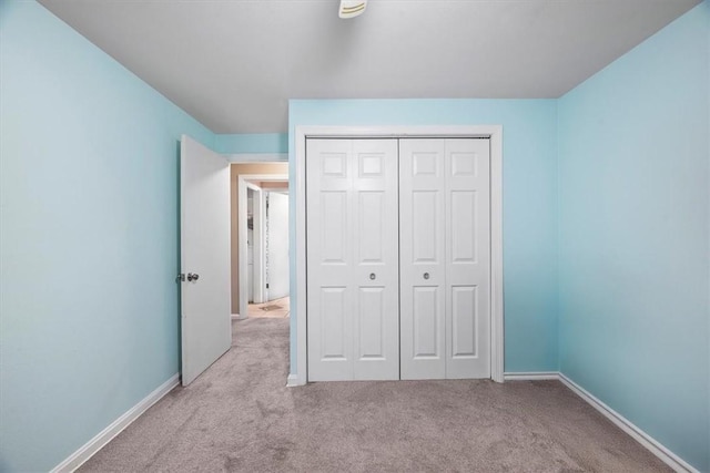 unfurnished bedroom featuring light carpet and a closet