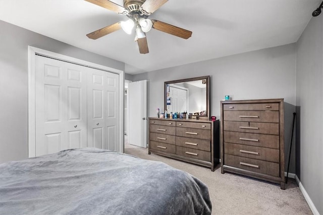 bedroom with ceiling fan, light colored carpet, and a closet