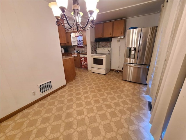 kitchen featuring stainless steel fridge, backsplash, pendant lighting, an inviting chandelier, and white range with electric cooktop