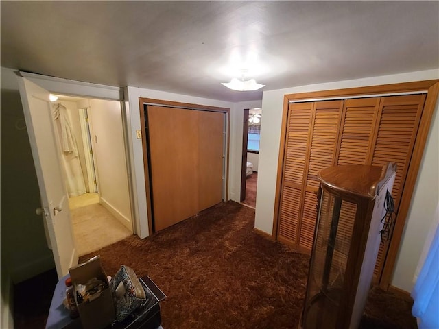 hallway featuring dark colored carpet