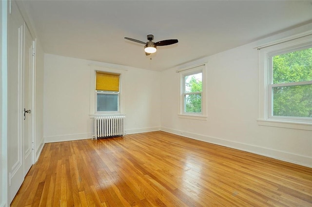 spare room with ceiling fan, radiator heating unit, and light hardwood / wood-style flooring