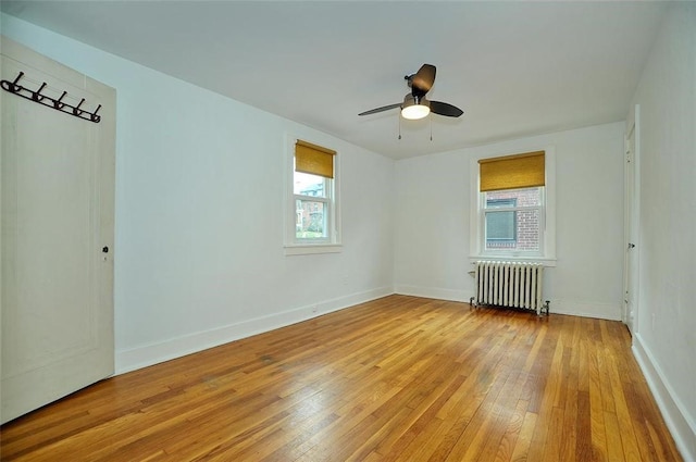 spare room with radiator, ceiling fan, plenty of natural light, and light hardwood / wood-style floors