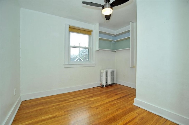 unfurnished room featuring ceiling fan, light wood-type flooring, and radiator heating unit