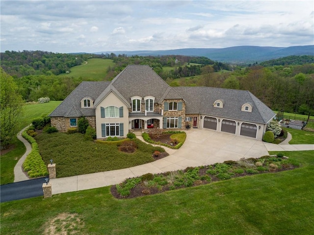 french country home with a mountain view, a front lawn, and a garage