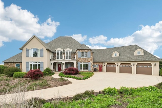 french country style house with an attached garage, concrete driveway, stucco siding, and stone siding