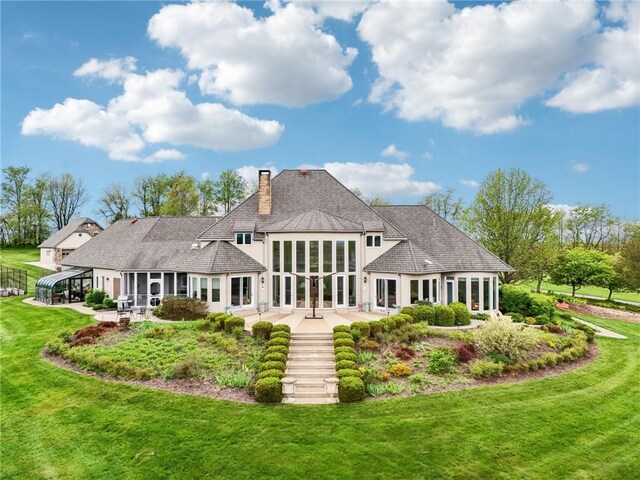 rear view of house featuring french doors, stucco siding, a chimney, a lawn, and a patio