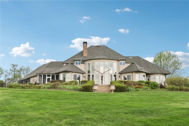 back of house featuring a lawn, a chimney, and stucco siding
