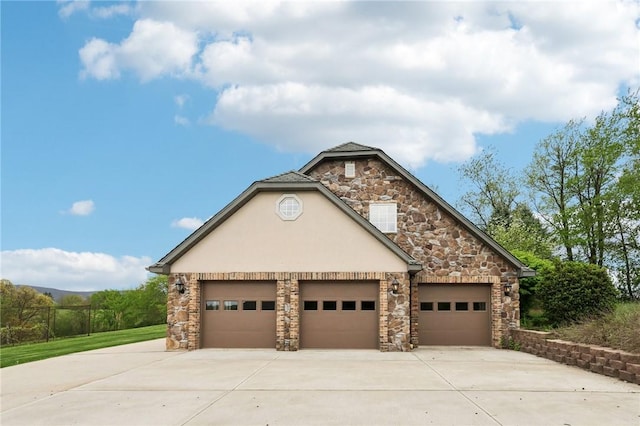 view of front facade with an attached garage, stucco siding, stone siding, and concrete driveway