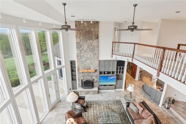 living area with a fireplace and a ceiling fan