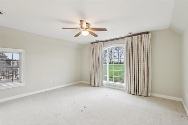 carpeted spare room featuring a ceiling fan, baseboards, and vaulted ceiling
